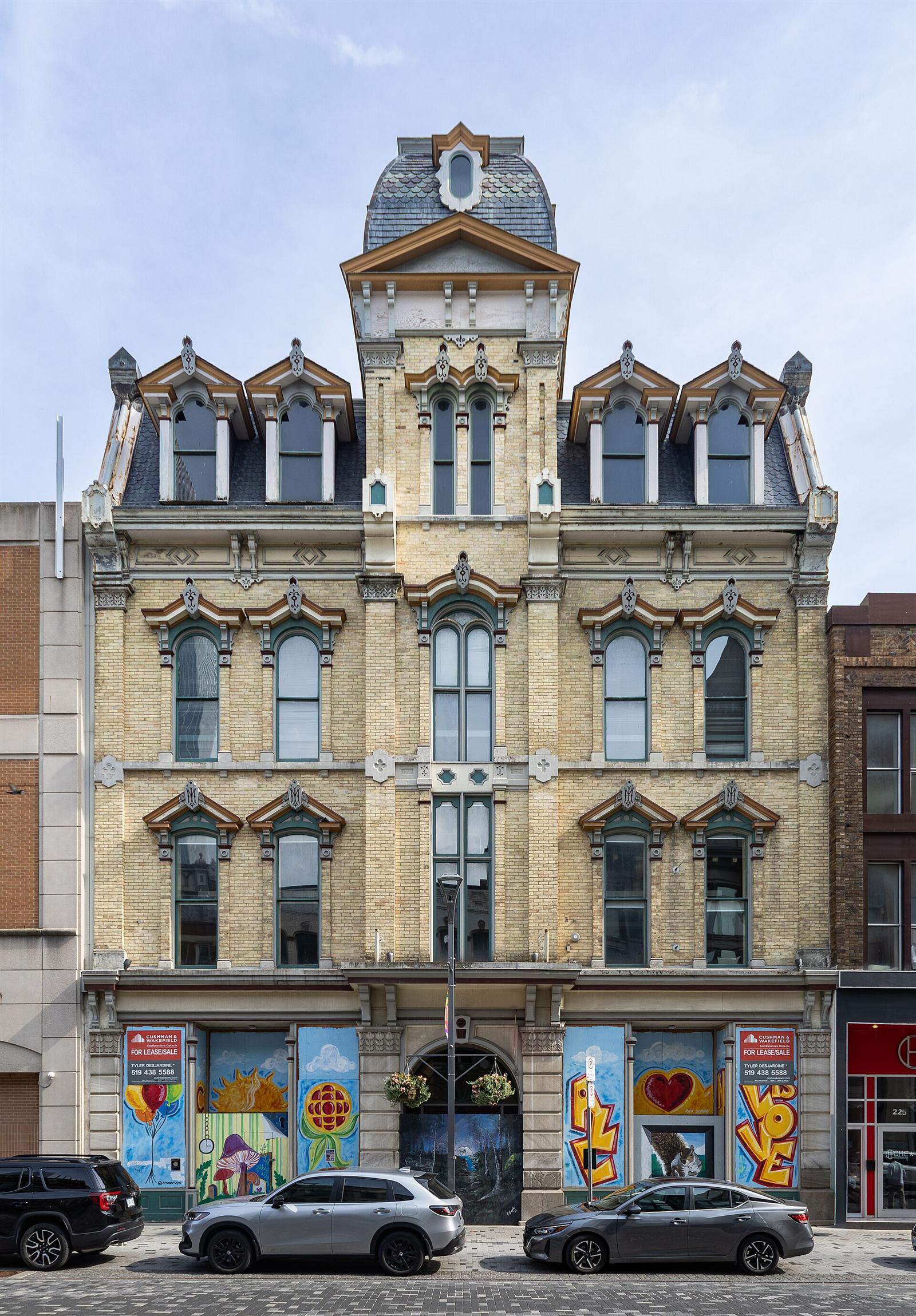 A restored Victorian building at 229 Dundas Street, London, Ontario, with painted murals on its shopfronts